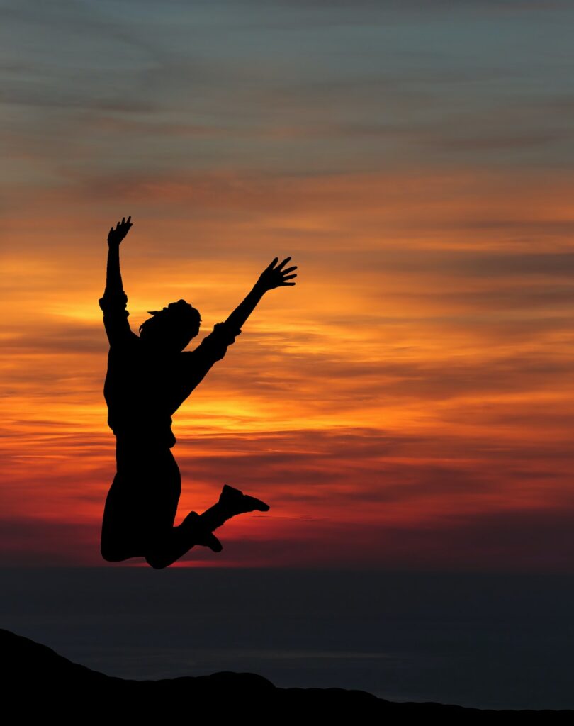 Happy woman jumping against beautiful sunset. Freedom, enjoyment concept.